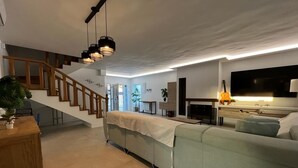 Una sala de estar moderna con una escalera, un sofá, un televisor y una guitarra.