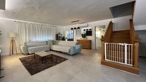 Una sala de estar moderna con un sofá seccional, una mesa de centro y una escalera con barandilla de madera.