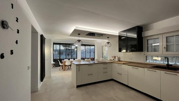 Una cocina moderna con armarios blancos, una isla central e iluminación colgante.