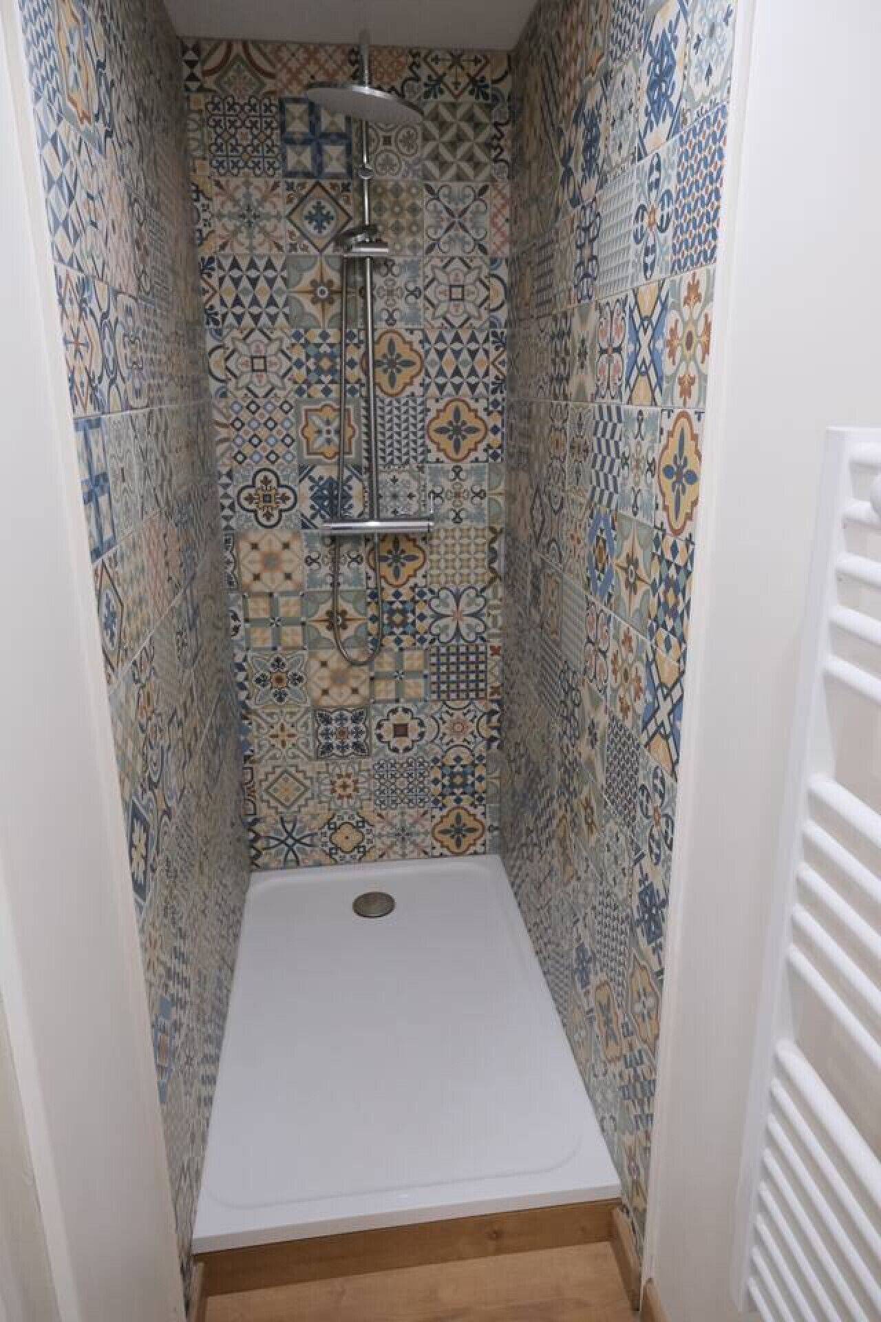 A small shower room with a tiled wall and a white floor.