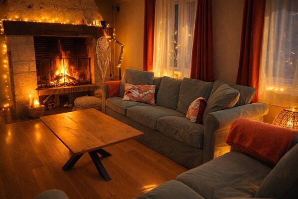 Una sala de estar acogedora con chimenea, un sofá, una mesa de centro y una lámpara.