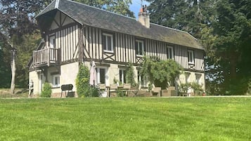 A traditional half-timbered house with a large front lawn and a chimney.