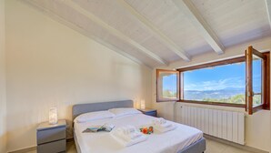 A bedroom with a bed, nightstands, a window with a view, and a radiator. - Cottage del Lago: Lake Maggiore Villa With Shared Pool (Laveno Mombello)