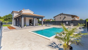 Une villa moderne dotée d’une piscine, d’un espace salon extérieur et d’un patio couvert.