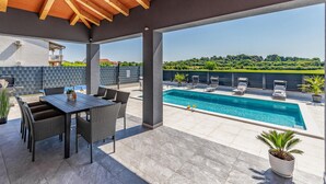 Un espace extérieur abrité comprenant une piscine, des chaises longues et une table avec des chaises.