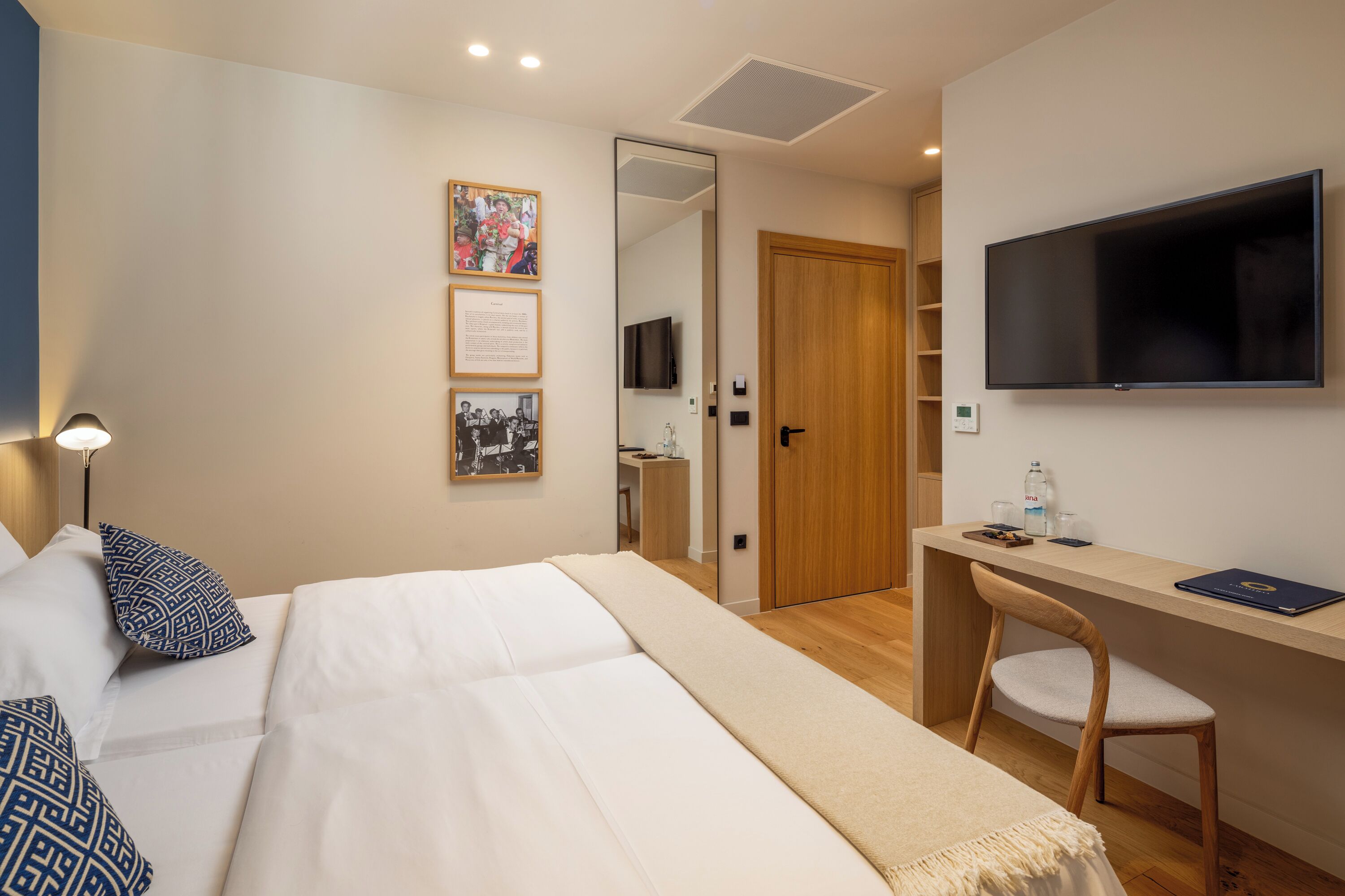 Una habitación de hotel con una cama, un escritorio, una silla, un televisor y una puerta que da a un baño.