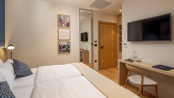 Una habitación de hotel con una cama, un escritorio, una silla, un televisor y una puerta que da a un baño.