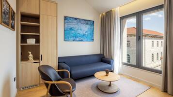 Un salon moderne avec un canapé, deux fauteuils, une table basse et une grande fenêtre agrémentée de rideaux.