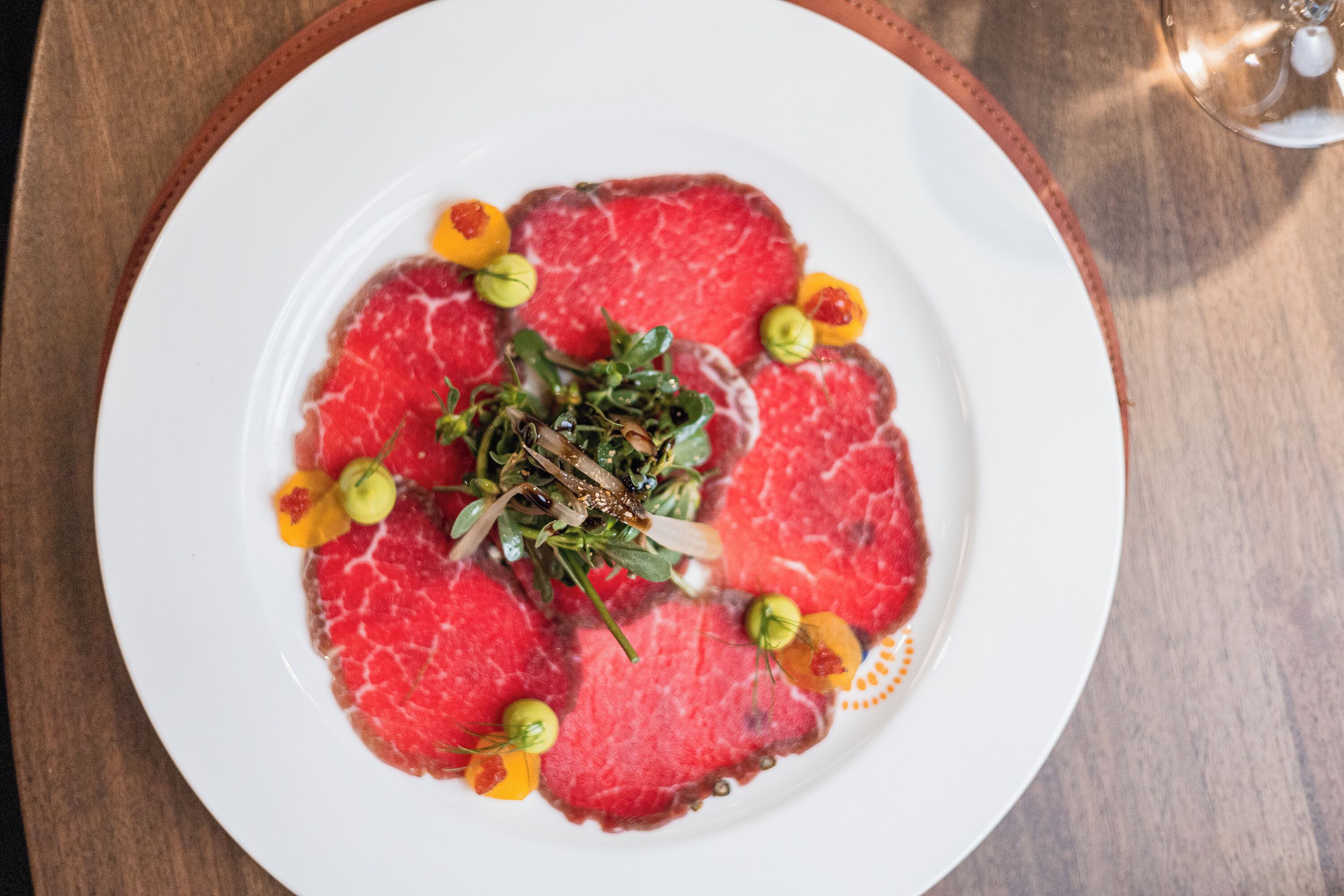 A plate of raw beef with garnishes on a white plate.