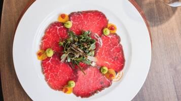 A plate of raw beef with garnishes on a white plate.