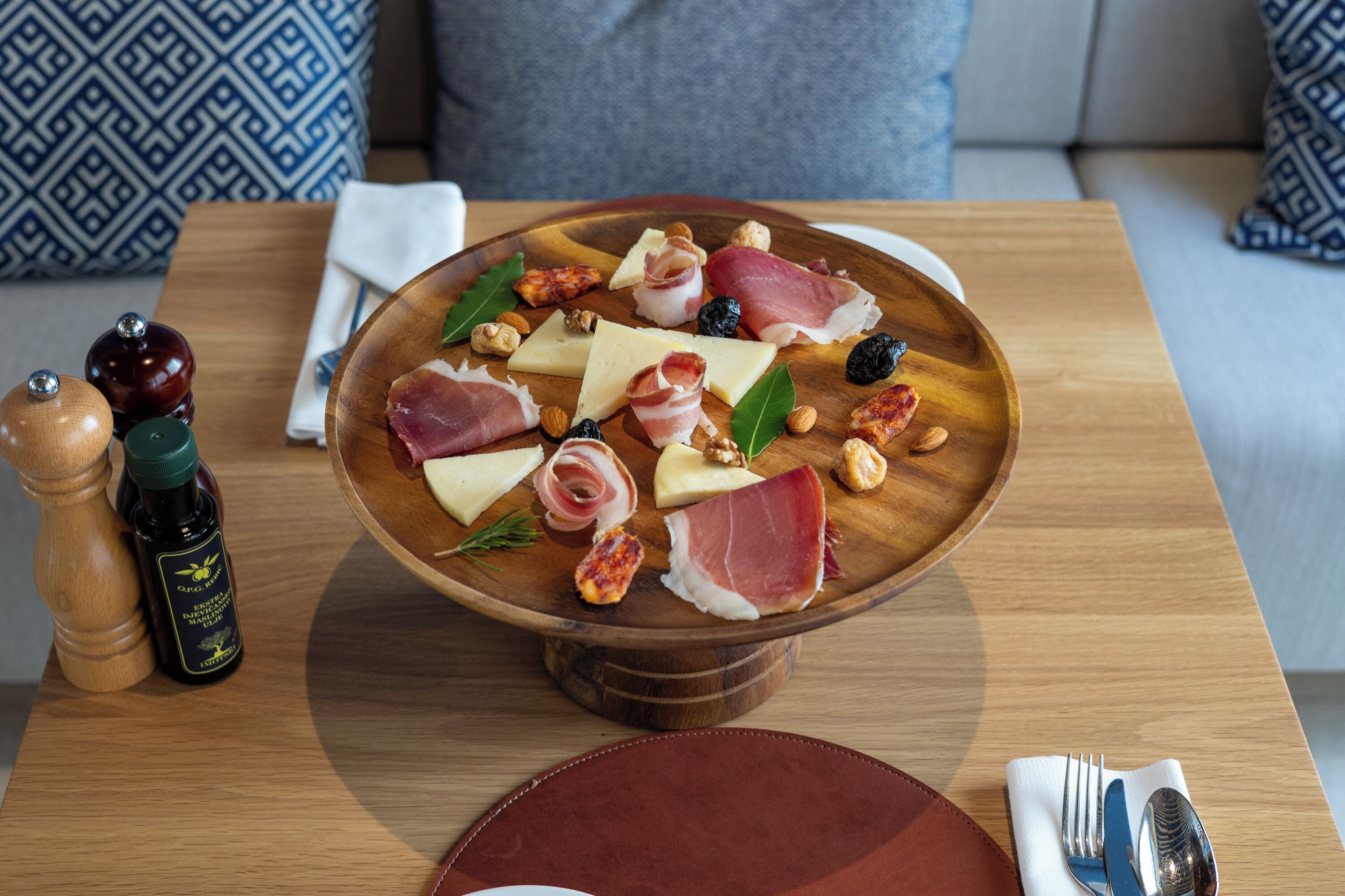 Una tabla de madera con varios quesos, carnes y nueces sobre una mesa.