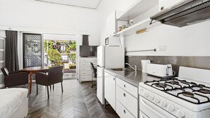Een moderne keuken met een gasfornuis, een koelkast en een eethoek met een tafel en stoelen.