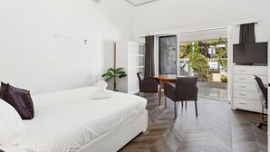 Een moderne slaapkamer met een bed, een bureau en een stoel. Op het bureau staat een plant en er is een raam met uitzicht op het omliggende landschap.