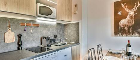 A modern kitchen with a dishwasher, microwave, and a dining area with a table set for two.