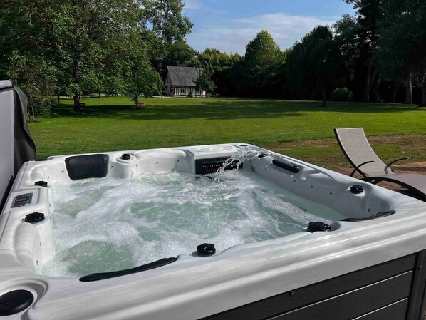 A hot tub outdoors with a grassy area and trees in the background.