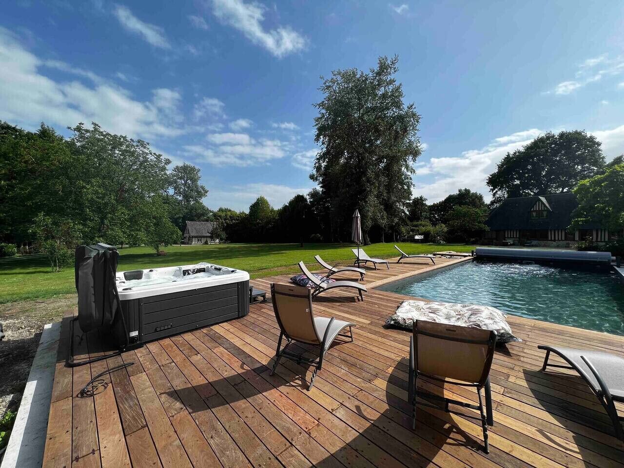 Une terrasse avec un jacuzzi, des chaises longues et une piscine.