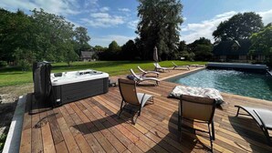 Une terrasse avec un jacuzzi, des chaises longues et une piscine.