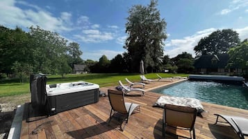 Une terrasse avec un jacuzzi, des chaises longues et une piscine.