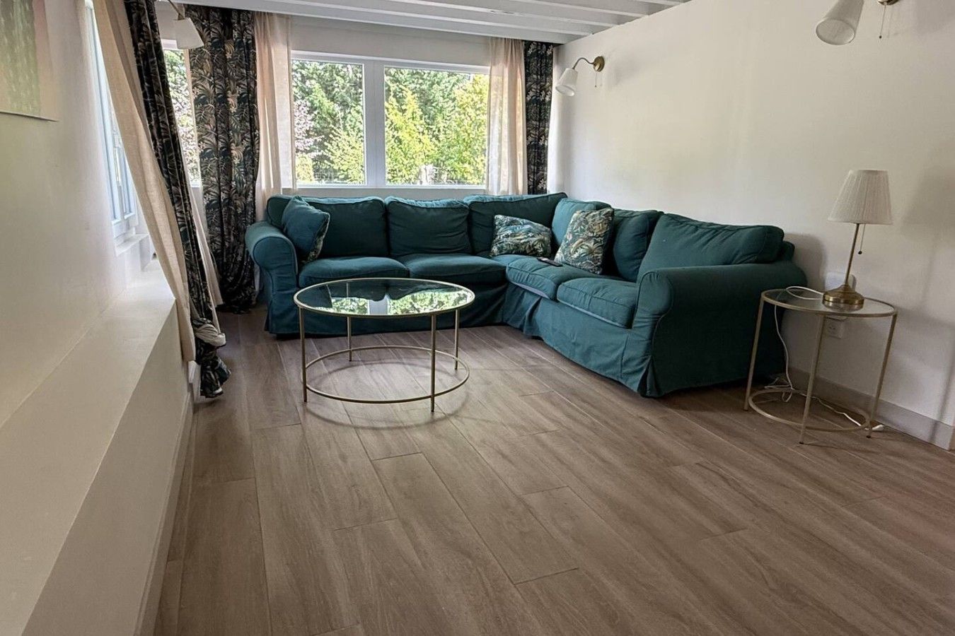 Ein Wohnzimmer mit einem grünen Sofa, einem runden Couchtisch und einer Lampe.