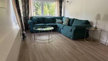 Ein Wohnzimmer mit einem grünen Sofa, einem runden Couchtisch und einer Lampe.