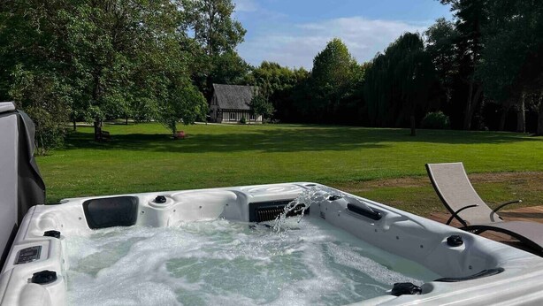 Un bain à remous en plein air, avec une pelouse et des arbres en arrière-plan.