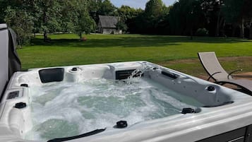Un bain à remous en plein air, avec une pelouse et des arbres en arrière-plan.