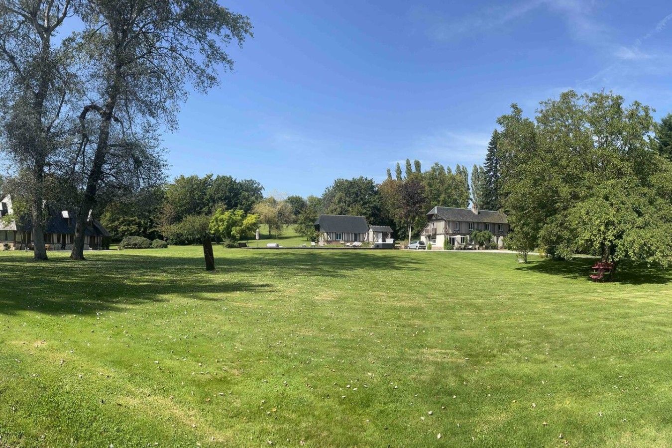 A well-maintained grassy area with trees and a building in the background.