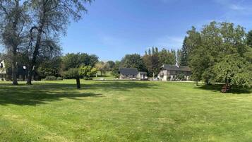 A well-maintained grassy area with trees and a building in the background.