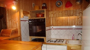 A compact kitchen with wooden cabinets, a stove, a dishwasher, and a sink. - Central Apartment for 5, Near Slopes & Shops, Crest-Voland (Crest-Voland)