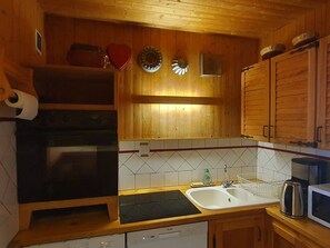 A kitchen with wooden cabinets, a stove, a microwave, and a sink.