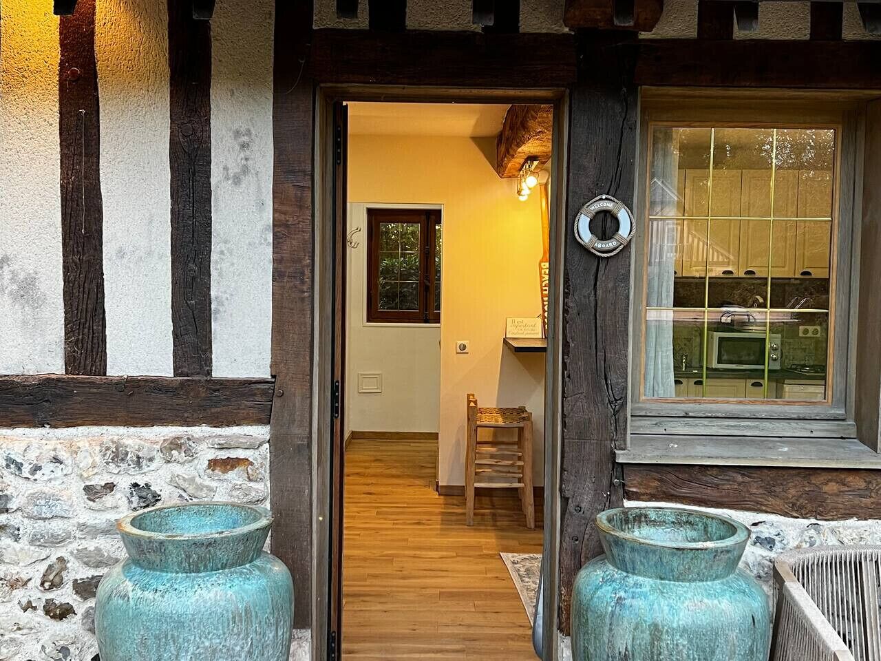 Een houten deur die leidt naar een kamer met een raam, een stoel en een bord.