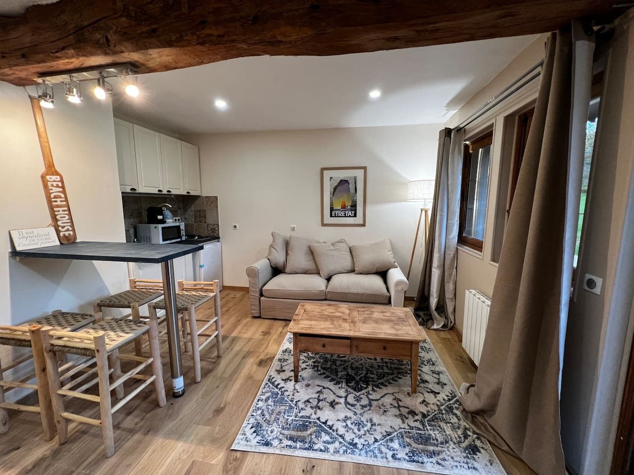 A compact living space with a kitchenette, a sofa, a coffee table, and a patterned rug.