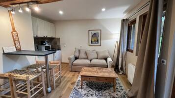 A compact living space with a kitchenette, a sofa, a coffee table, and a patterned rug.