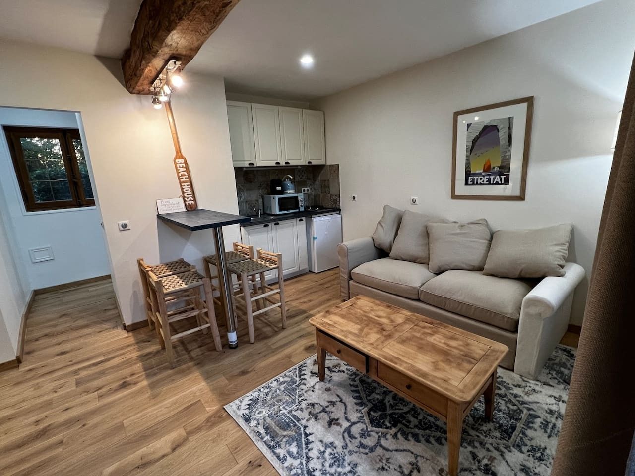 A compact living space with a kitchenette, a dining area with chairs, a sofa, and a coffee table.