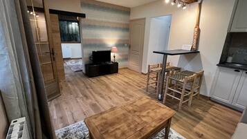 A cozy living room with a wooden coffee table, a TV, and a dining area with wicker chairs.