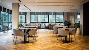 A modern dining area with wooden flooring, multiple tables, and chairs. - SAM E Hotel Bangkok Sathorn (Bangkok)