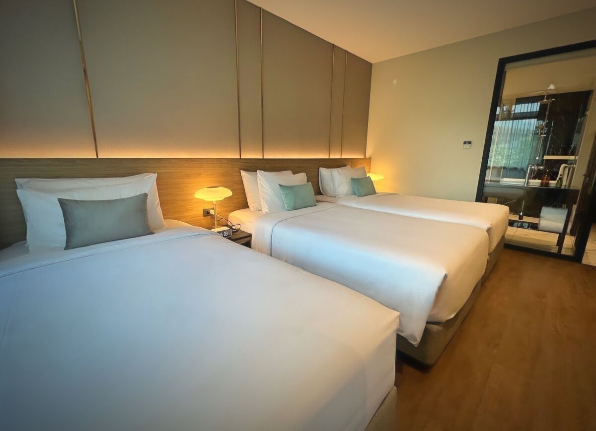 Een hotelkamer met twee bedden, een nachtkastje en een spiegel.