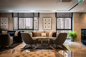 A modern living room with a sofa, two rocking chairs, a coffee table, and a potted plant. - SAM E Hotel Bangkok Sathorn (Bangkok)