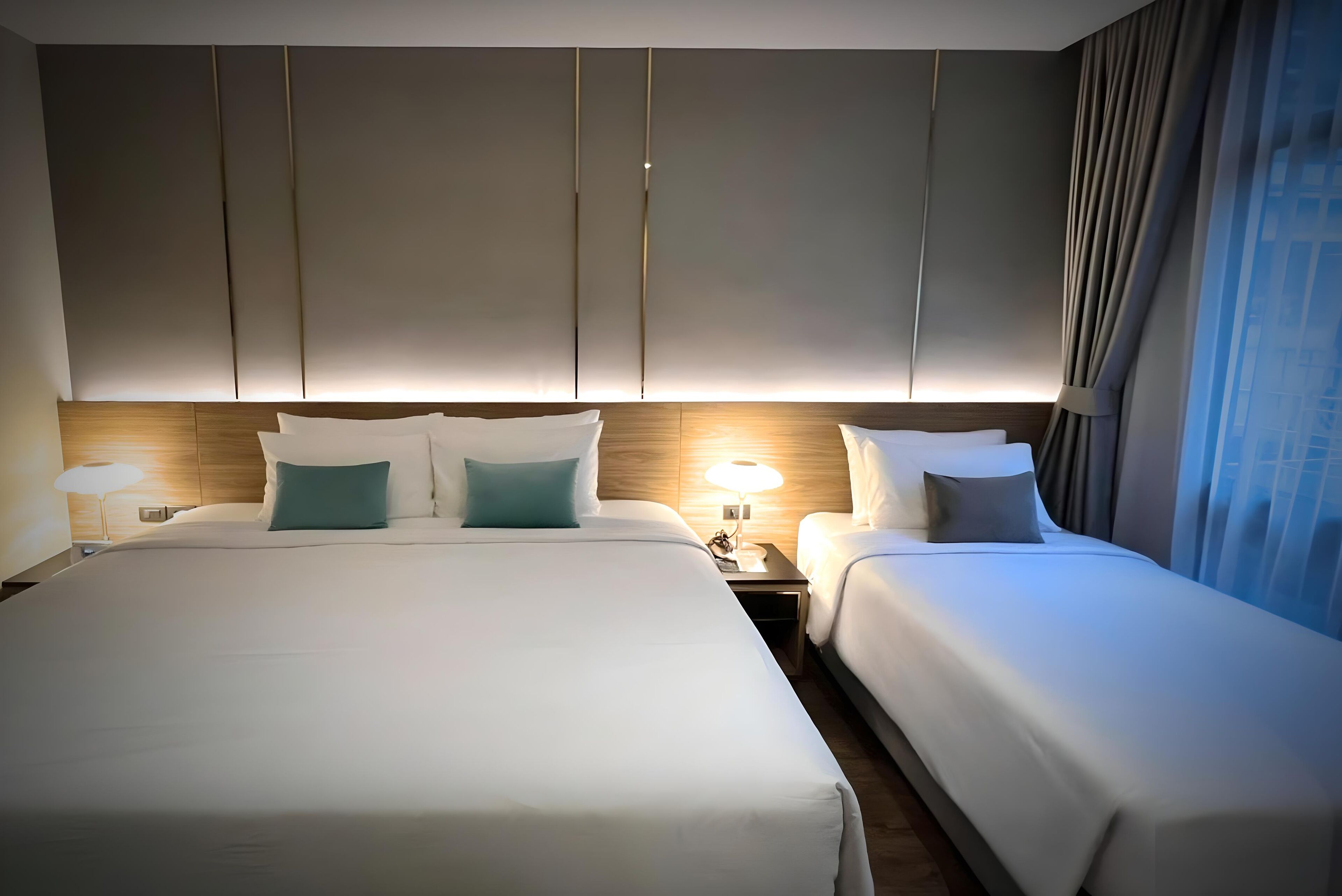 Et hotelværelse med to senge, et træhovedgærde og et natbord med en lampe.