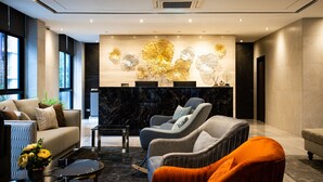 A modern lobby with a marble reception desk, comfortable seating, and a large wall art piece. - SAM E Hotel Bangkok Sathorn (Bangkok)