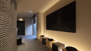 A modern hallway with a brick wall, a large abstract painting, and a series of black and beige planters. - kyohotel kishotei goshominami (Kyoto)