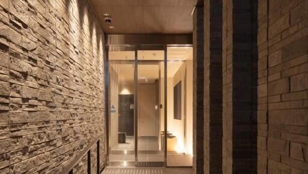A corridor with stone walls and a tiled floor, leading to a glass door. - kyohotel kishotei goshominami (Kyoto)