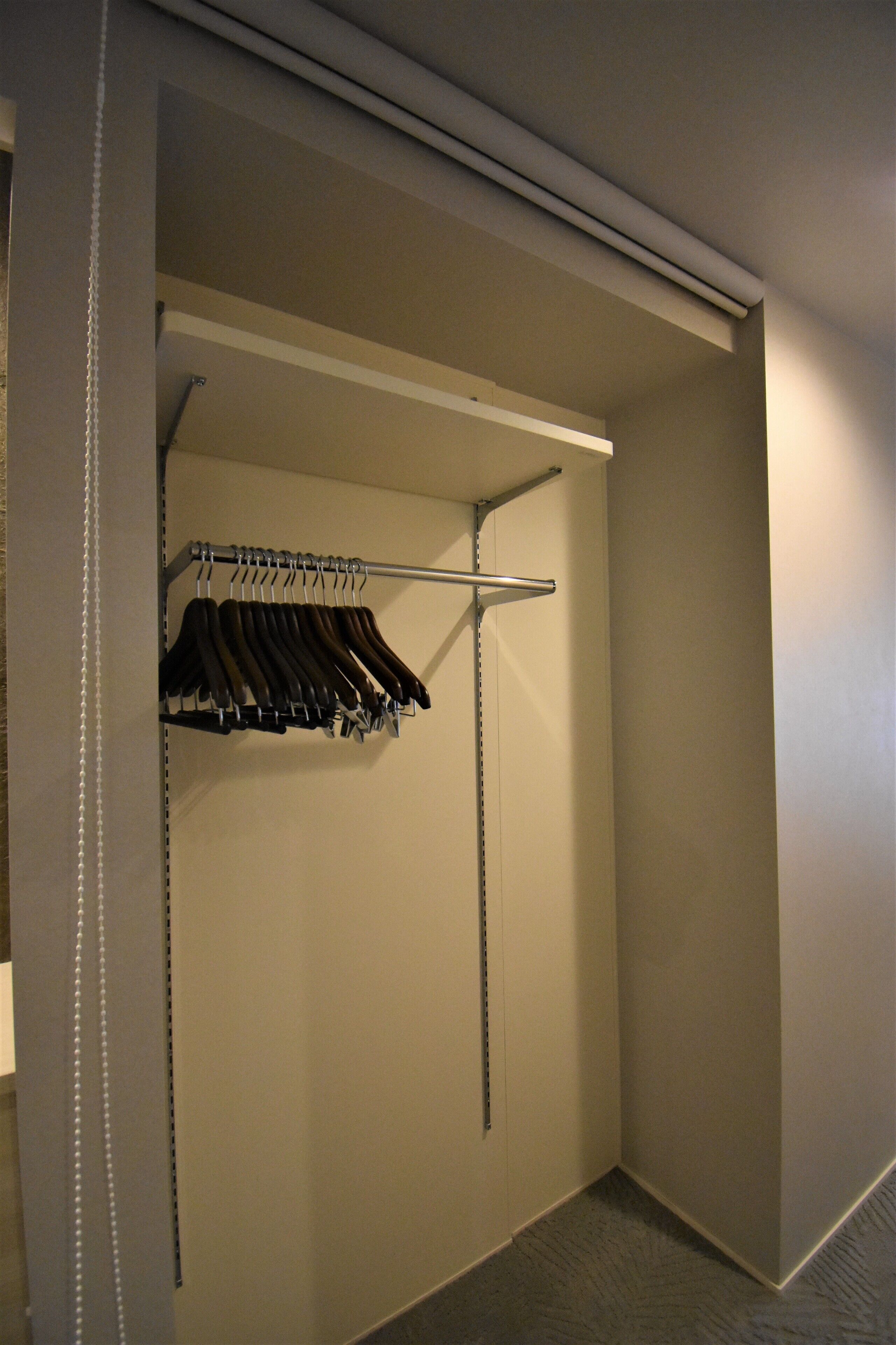 A walk-in closet with a metal rod rack holding several hangers.