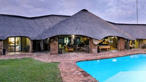 A thatched-roof building with a swimming pool and stone pathways.