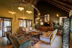 A spacious living area with a sofa, armchairs, a coffee table, and hanging lights. - Sable Ranch Bush Lodge  (Brits)