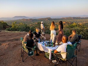 A group of people seated around a table with a view of a mountainous landscape.