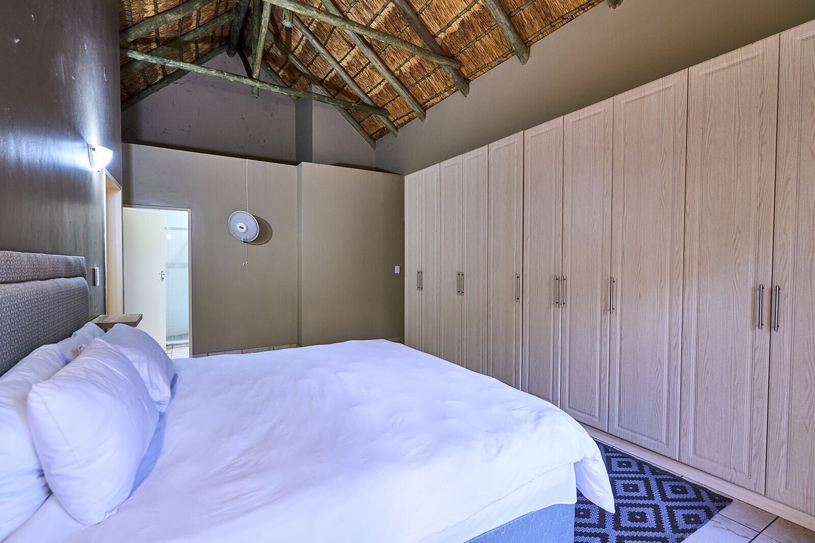 Quarto com cama, guarda-roupa e teto de colmo.
