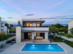 Une maison moderne à deux étages avec une piscine située dans le jardin avant.