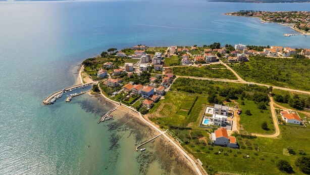 Luchtbeeld van een kustgebied met woonhuizen, een jachthaven en een strand.