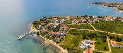 Vista aérea de una zona residencial costera con casas, un puerto deportivo y una playa.